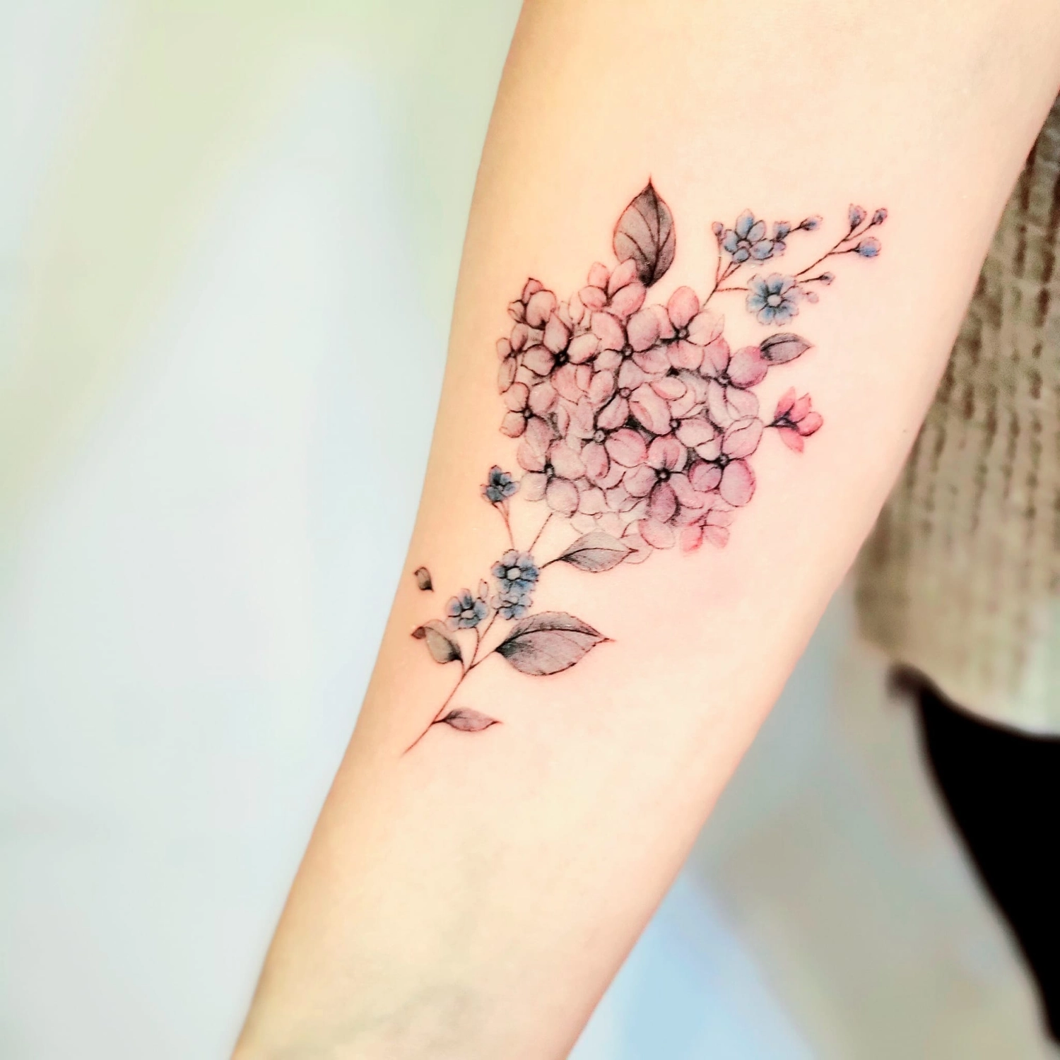 A Fleur de Peau - Professionelles Tattoo Studio - Tätowierung am Arm einer Person