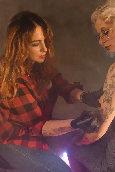 A Fleur de Peau - Professionellen Tattoo Studio - Eine Frau tätowiert den Arm einer anderen Frau